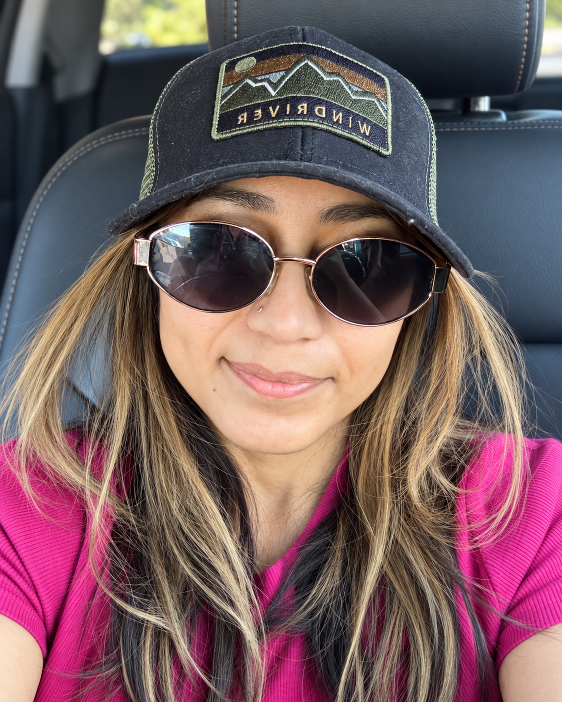 Portrait of Qurratul wearing sunglasses, a baseball cap, and a pink top